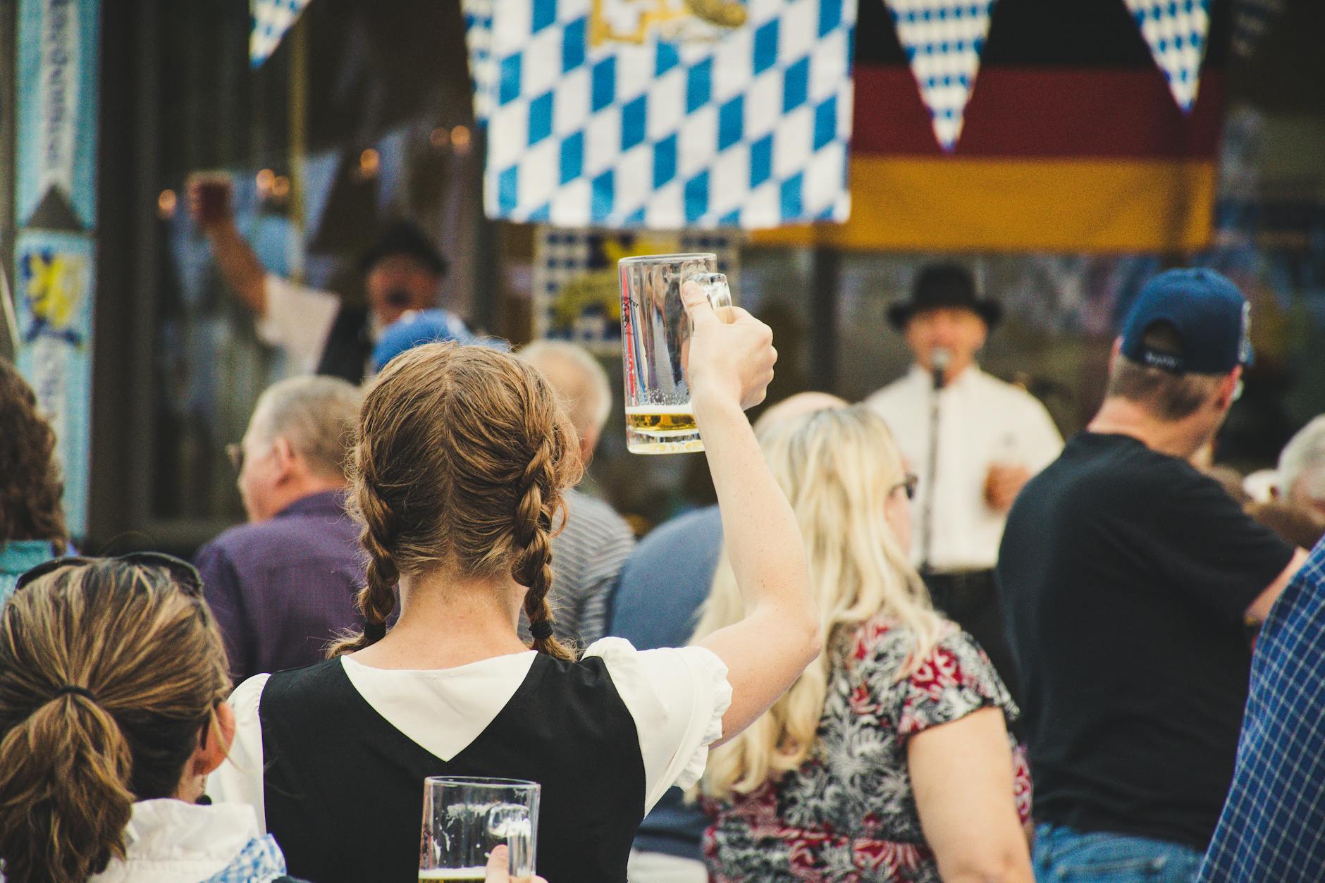 Tłum wiwatuje z kuflami piwa na plenerowym festynie Oktoberfest