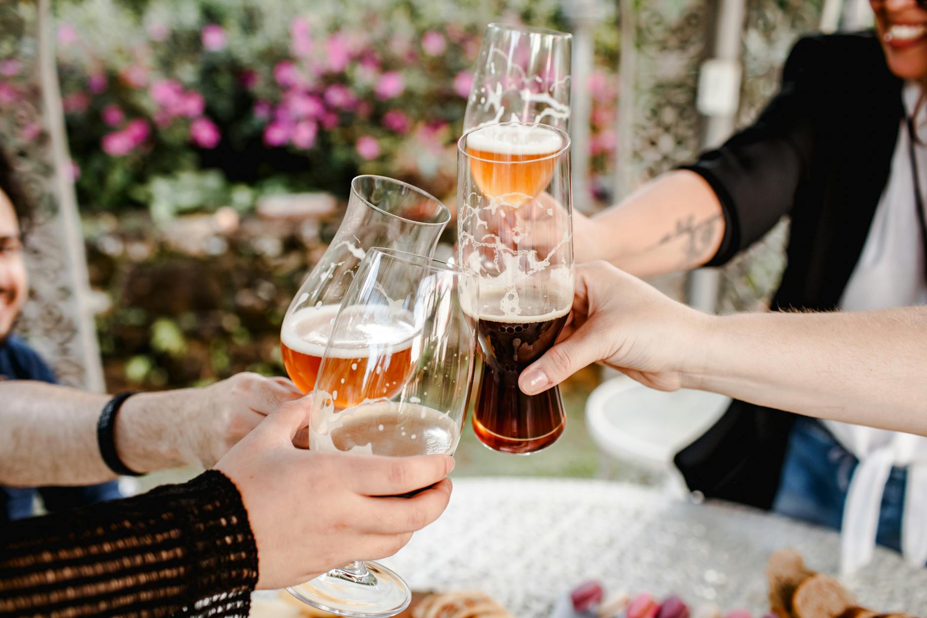 Znajomi wznoszą kufle z piwem rzemieślniczym podczas ogrodowego spotkania